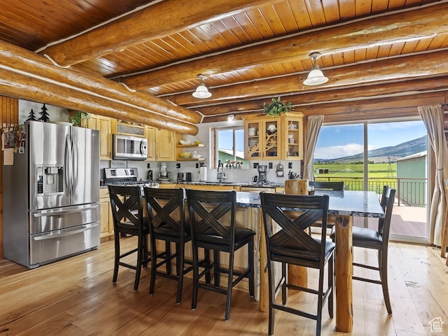 kitchen with beam ceiling, wood ceiling, appliances with stainless steel finishes, and light wood-type flooring