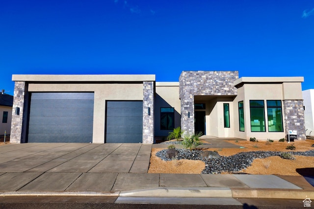 contemporary home featuring an attached garage, driveway, stucco siding, and stone siding