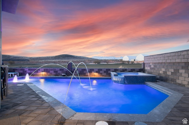 1560 W Torrey Pines Rd, Hurricane, UT 84737 - pool at dusk featuring pool water feature, a mountain view, a patio area, and an in ground hot tub