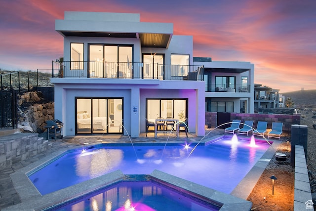 1560 W Torrey Pines Rd, Hurricane, UT 84737 - back house at dusk with a balcony, a patio area, pool water feature, and a swimming pool with hot tub