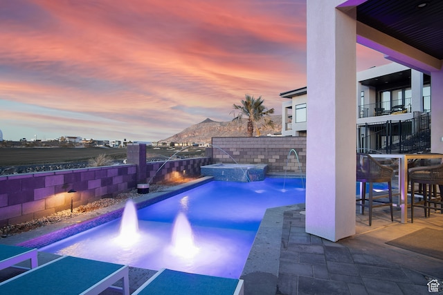 1560 W Torrey Pines Rd, Hurricane, UT 84737 - pool at dusk with pool water feature, a mountain view, and a patio