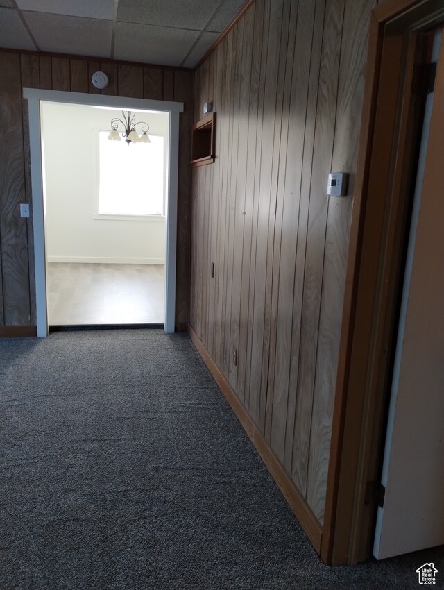 182 E 9000 S, Sandy, UT 84070 - corridor with dark carpet, wood walls, a drop ceiling, and an inviting chandelier