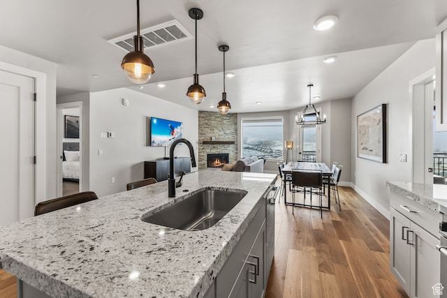 909 W Peace Tree Trl Unit 507, Heber City, UT 84032 - kitchen featuring sink, pendant lighting, light stone counters, light hardwood / wood-style floors, and a stone fireplace