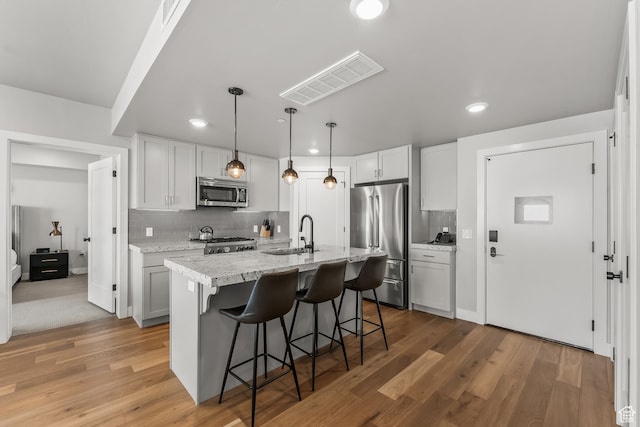 909 W Peace Tree Trl Unit 507, Heber City, UT 84032 - kitchen featuring white cabinetry, sink, light hardwood / wood-style flooring, stainless steel appliances, and tasteful backsplash