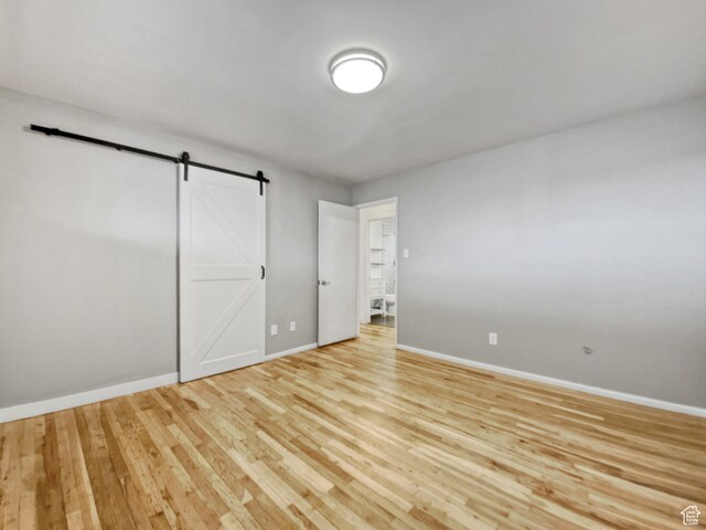 650 N 300 W Unit 218, Salt Lake City, UT 84103 - unfurnished bedroom featuring light hardwood / wood-style flooring and a barn door