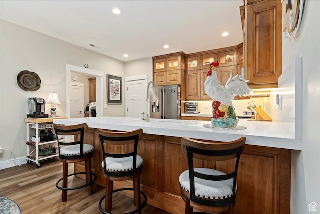 kitchen with dark wood-type flooring, a breakfast bar, sink, kitchen peninsula, and high end fridge