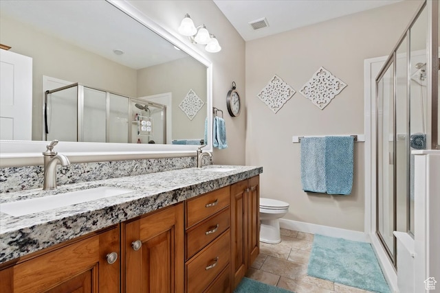 bathroom with walk in shower, double sink vanity, tile floors, and toilet