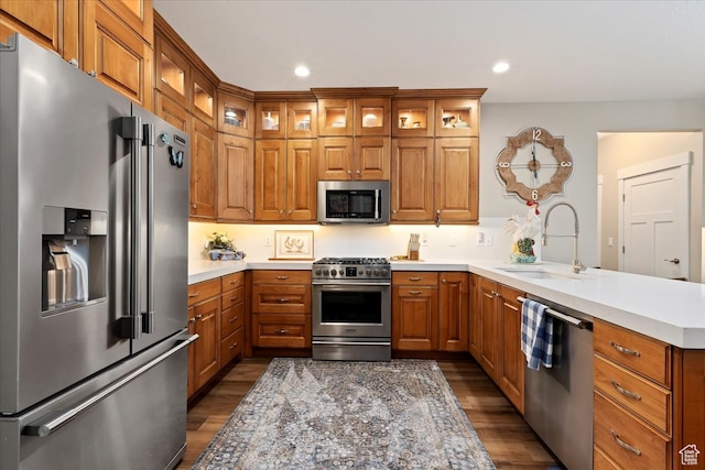 kitchen featuring high end appliances, dark hardwood / wood-style floors, kitchen peninsula, and sink