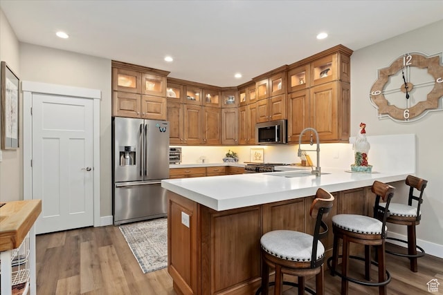 kitchen featuring a kitchen bar, wood-type flooring, appliances with stainless steel finishes, and sink