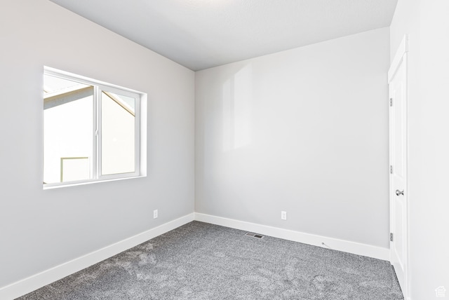 unfurnished room with dark colored carpet
