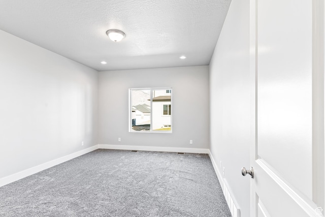 empty room with a textured ceiling and light colored carpet