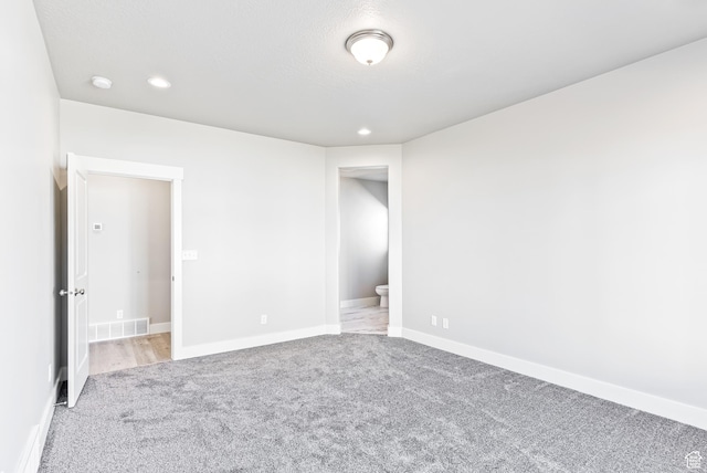 interior space featuring ensuite bath and light carpet