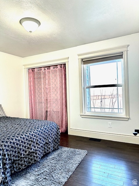bedroom with dark wood-type flooring and a textured ceiling