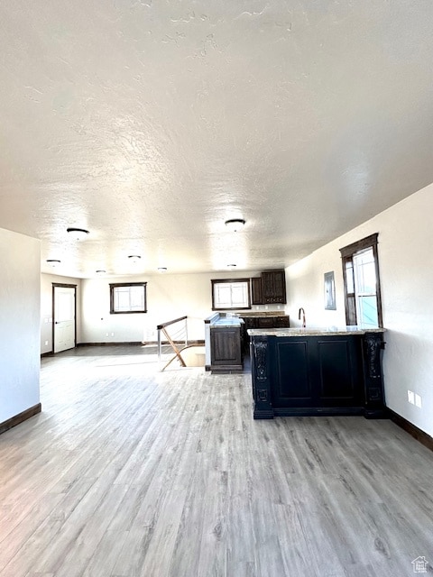 unfurnished living room with light hardwood / wood-style flooring and a textured ceiling