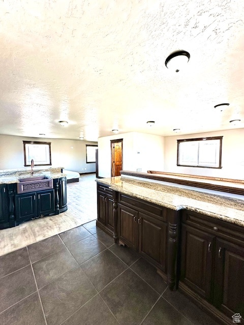 kitchen featuring dark tile patterned flooring, sink, a textured ceiling, and dark brown cabinetry