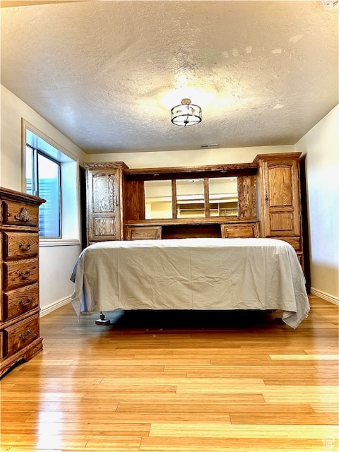 bedroom featuring light hardwood / wood-style floors and a textured ceiling