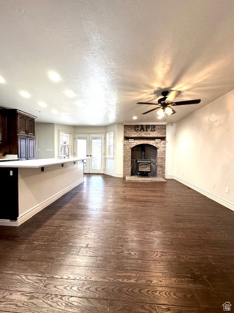 unfurnished living room with ceiling fan, dark hardwood / wood-style floors, and a textured ceiling
