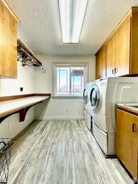 clothes washing area with a textured ceiling, light hardwood / wood-style floors, cabinets, and independent washer and dryer