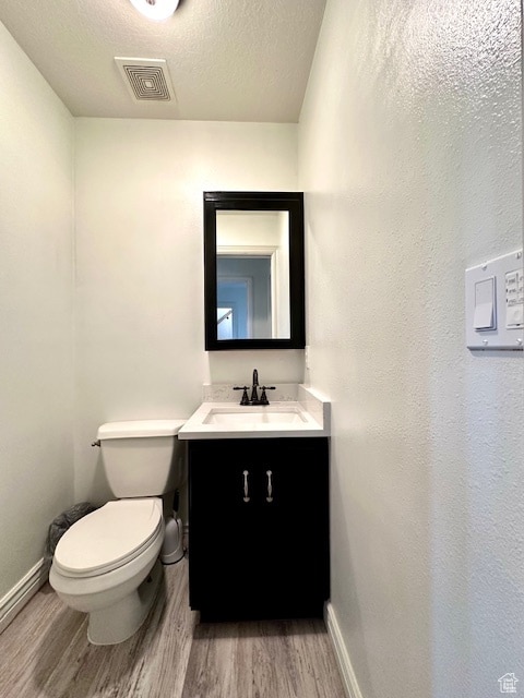 bathroom featuring vanity, hardwood / wood-style flooring, a textured ceiling, and toilet