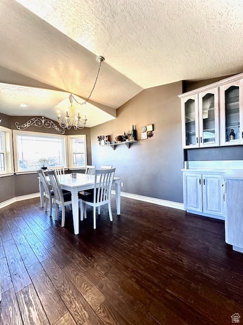 unfurnished dining area with an inviting chandelier, a textured ceiling, dark hardwood / wood-style floors, and lofted ceiling