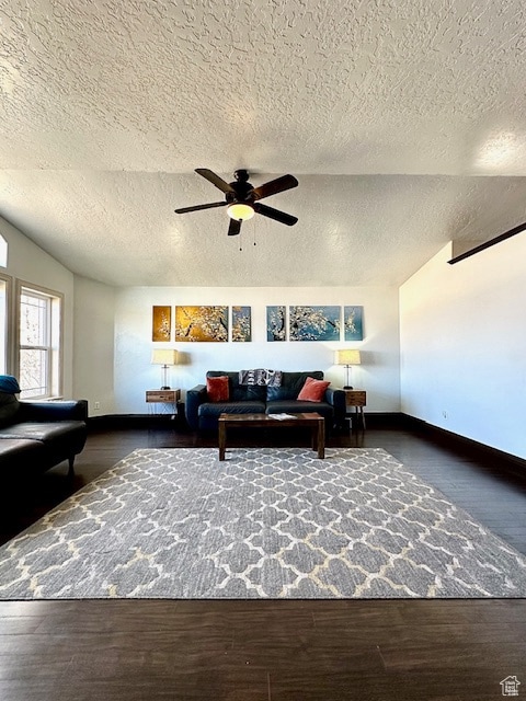 living room with ceiling fan, dark hardwood / wood-style floors, and a textured ceiling