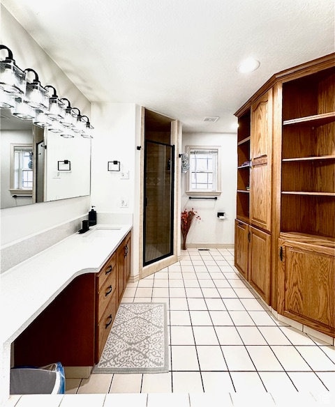 bathroom featuring a shower with door, tile patterned floors, and vanity