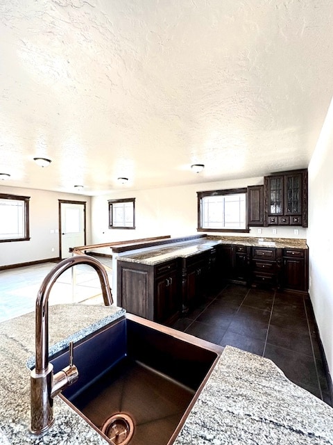 kitchen featuring sink, dark brown cabinetry, plenty of natural light, and dark tile patterned floors