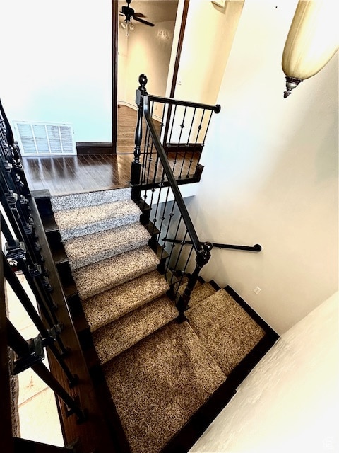 stairs featuring hardwood / wood-style flooring and ceiling fan