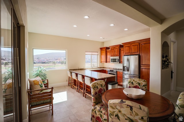 836 E St James Ln, St George, UT 84790 - kitchen featuring appliances with stainless steel finishes, kitchen peninsula, sink, light tile flooring, and a kitchen breakfast bar