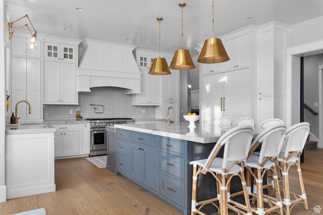 3297 W Blue Springs Ln, Bluffdale, UT 84065 - kitchen with backsplash, high end stainless steel range oven, hanging light fixtures, custom range hood, and white cabinetry