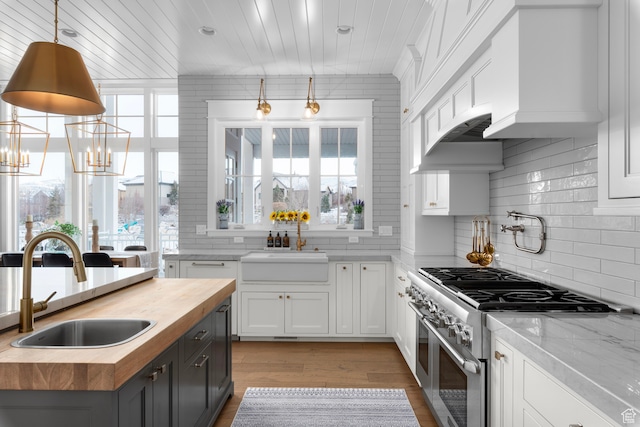 3297 W Blue Springs Ln, Bluffdale, UT 84065 - kitchen featuring white cabinetry, sink, high end range, and hanging light fixtures