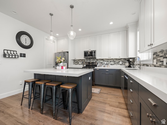 632 W 1460 S, Spanish Fork, UT 84660 - kitchen with white cabinetry, a kitchen island, stainless steel appliances, light hardwood / wood-style flooring, and hanging light fixtures