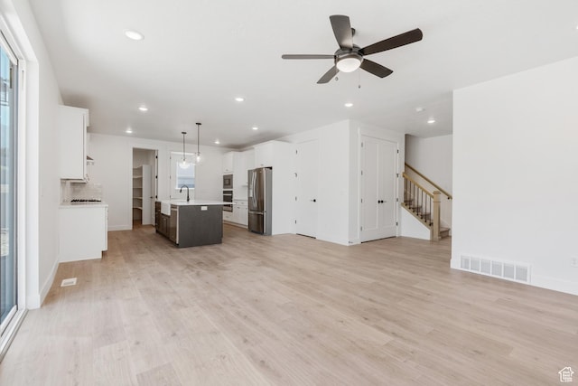 1263 Crest Dale Ln, Santaquin, UT 84655 - unfurnished living room with stairs, visible vents, light wood-style floors, and ceiling fan
