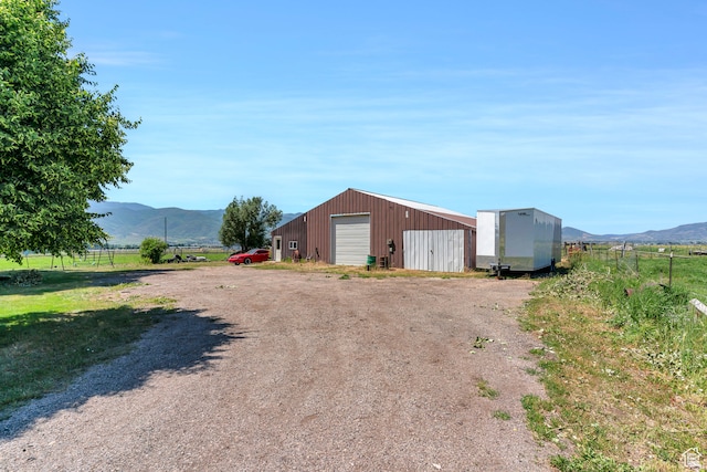 view of front of home with a mountain view, a rural view, an outdoor structure, and a garage
