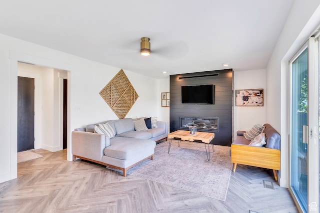 living room with light parquet floors, a large fireplace, and ceiling fan