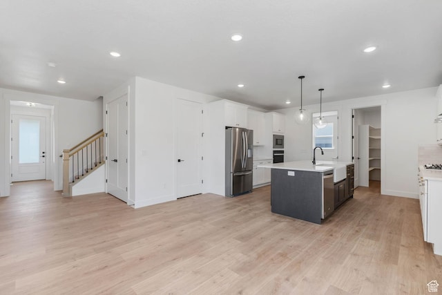1208 W View Dr S, Santaquin, UT 84655 - kitchen featuring stainless steel appliances, light countertops, an island with sink, light wood finished floors, and white cabinets