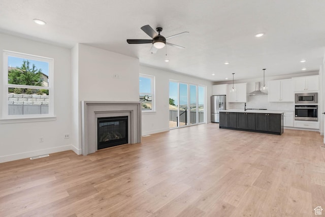 1203 Crest Dale Ln, Santaquin, UT 84655 - unfurnished living room featuring visible vents, light wood finished floors, ceiling fan, recessed lighting, and a glass covered fireplace