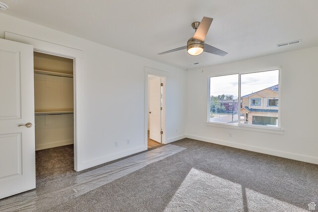 112 E 730 N Unit 102, Tooele, UT 84074 - unfurnished bedroom featuring ceiling fan, a closet, dark carpet, and a walk in closet