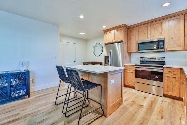 112 E 730 N Unit 102, Tooele, UT 84074 - kitchen with a center island, a breakfast bar area, appliances with stainless steel finishes, and light wood-type flooring