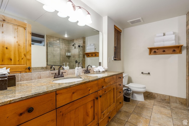 bathroom with toilet, oversized vanity, tiled shower, dual sinks, and tile flooring