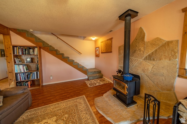 living room with hardwood / wood-style floors, a textured ceiling, and a wood stove