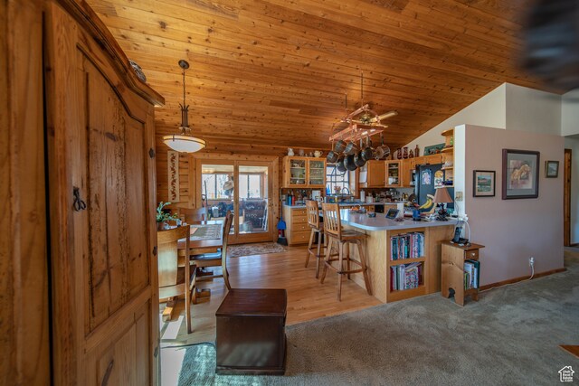 kitchen featuring pendant lighting, lofted ceiling, a kitchen breakfast bar, kitchen peninsula, and wooden ceiling