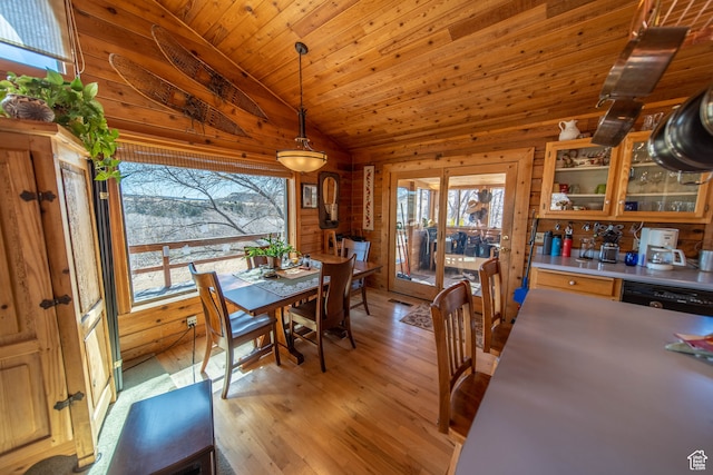 dining area with vaulted ceiling, wood ceiling, light wood-type flooring, and wood walls