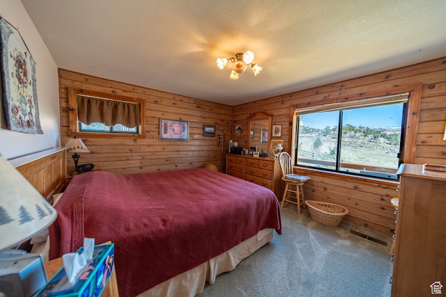 bedroom with wood walls, a textured ceiling, and carpet