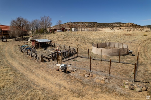 view of yard with an outbuilding, a mountain view, and a rural view
