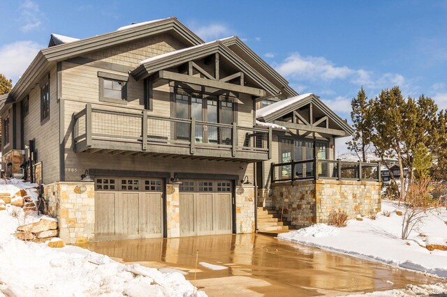 view of front of home featuring a balcony, stone siding, and an attached garage