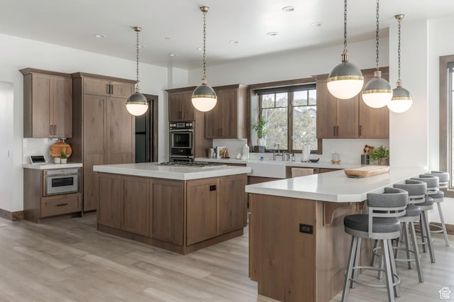 1905 E Kings Peak Cir, Heber City, UT 84032 - kitchen with brown cabinets, pendant lighting, light countertops, and light wood-style flooring