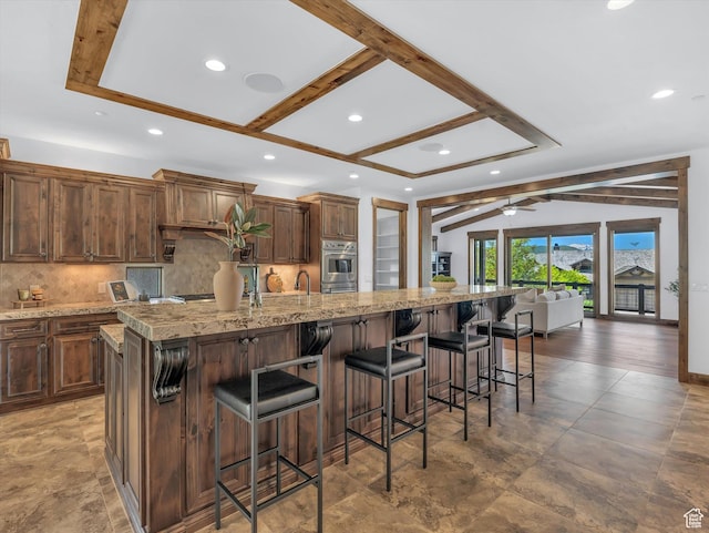 1707 E Kings Peak Cir N, Heber City, UT 84032 - kitchen with backsplash, a breakfast bar area, light stone counters, recessed lighting, and beam ceiling