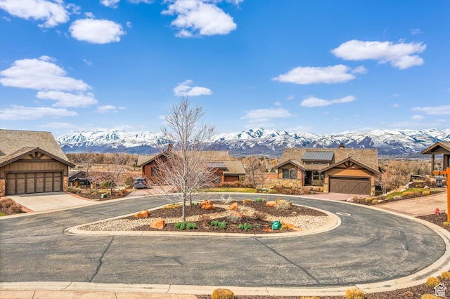 view of front of home with driveway, solar panels, a garage, stone siding, and a mountain view