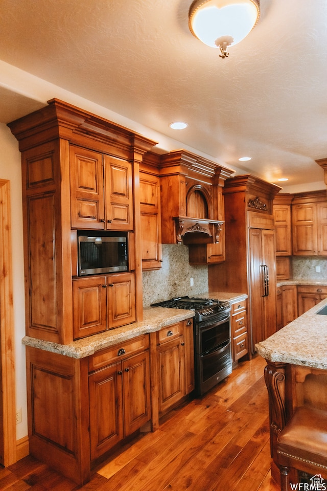 493 N 12500 W, Bluebell, UT 84007 - kitchen featuring light stone countertops, a breakfast bar area, stainless steel appliances, tasteful backsplash, and dark hardwood / wood-style flooring
